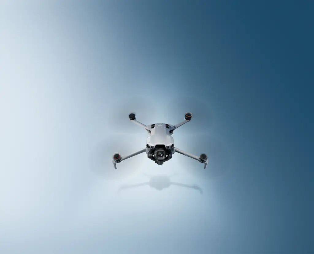DJI Mini 5 Pro flying against a blue studio background