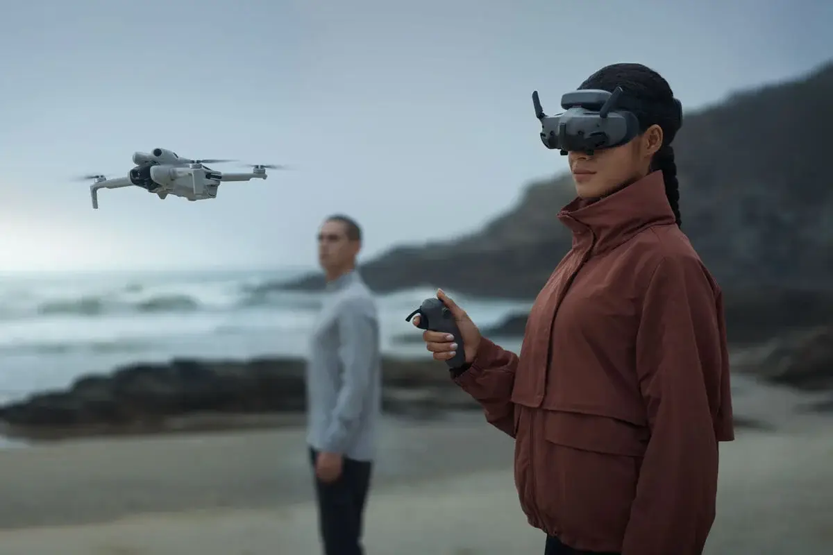 Pilot flying with DJI RC Motion 3 and goggles on a coastline